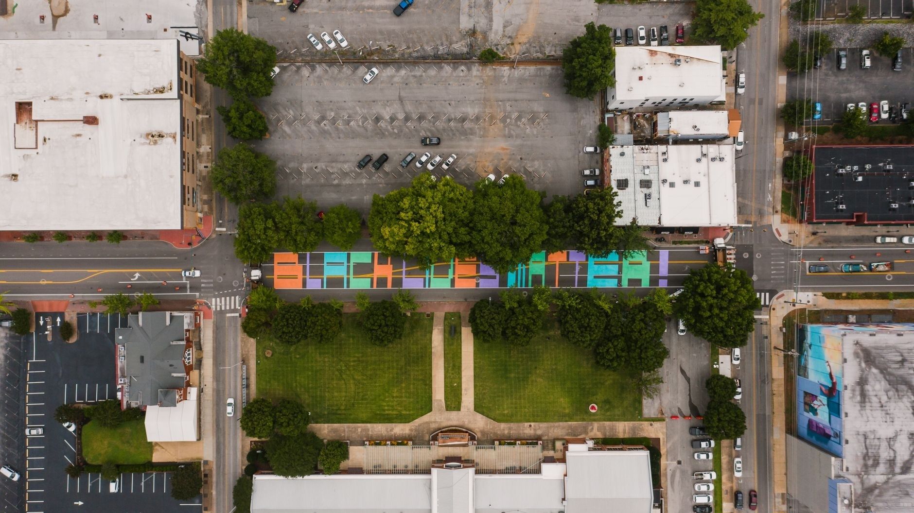 Aerial view of Ely Square park, colorful street mural, and downtown blocks