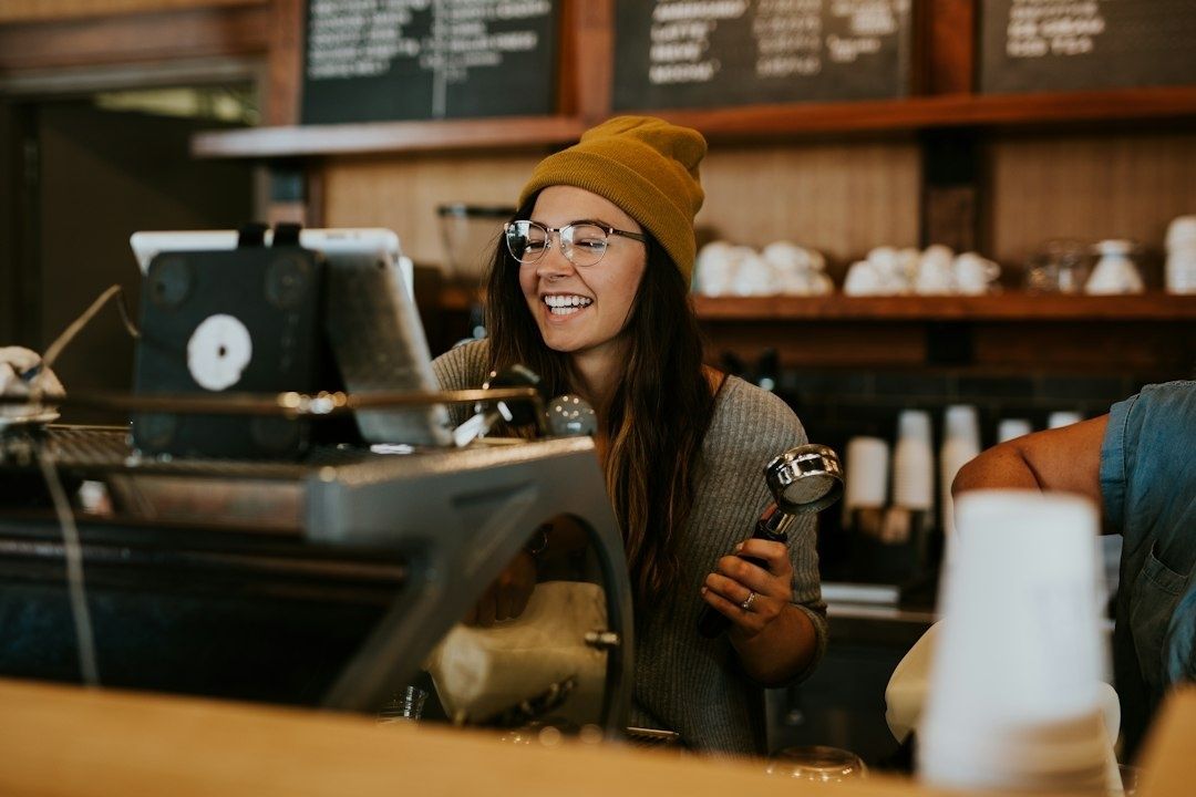Smiling barista working behind the counter at a neighborhood coffee shop